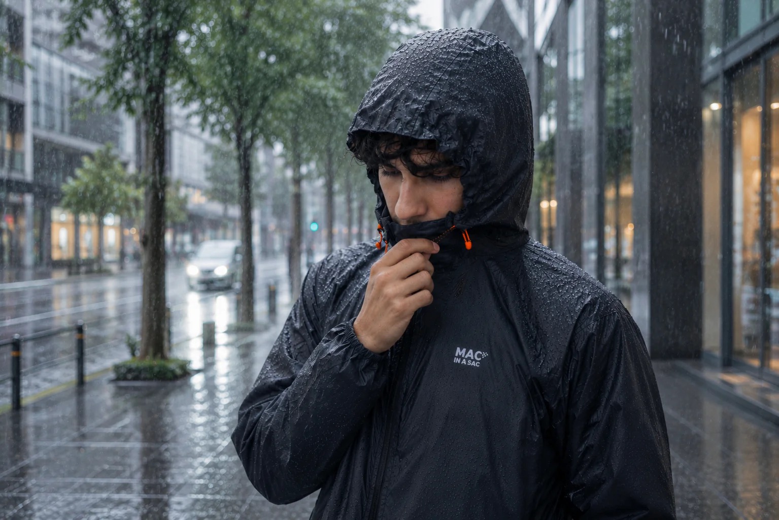 雨の街でMAC IN A SAC Originのフードをかぶる様子